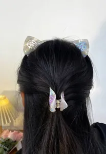Pinza a farfalla iridescente e fermagli a orecchie di gatto con fiocchi su capelli scuri