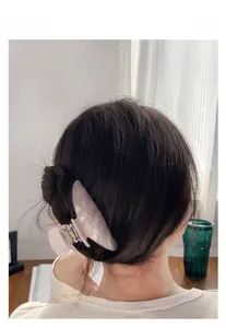 Detail of pink marble acrylic hair claw clip styled on woman's hair for a sleek look