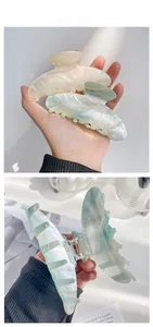 Detail of large iridescent pearl hair claws in cream and mint green with metal spring