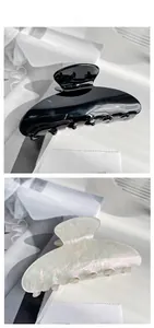 Close-up of large acrylic hair claws in glossy black and iridescent pearl white finish