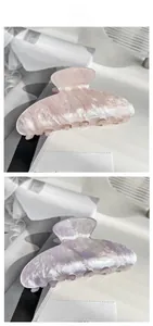 Detail of pink and purple acrylic hair claws with marble texture and glitter finish
