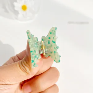 Mini pince à cheveux papillon à motif tacheté vert avec ressort doré sur base blanche