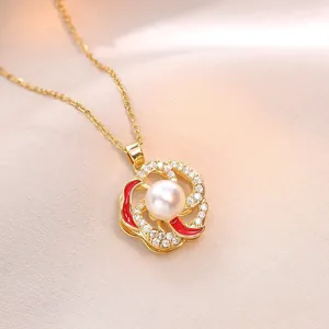 Elegant gold necklace featuring a rotating flower pendant with pearl and red enamel inlay