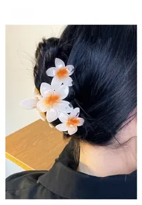 Vue détaillée d'une pince à cheveux avec fleurs de frangipanier portée sur un chignon