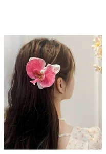 Detail showing orchid flower hair clip with pink petals and pearl on wavy hair