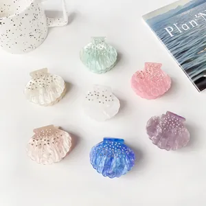 Seven shell-shaped resin hair claws with marble texture and rhinestones in various colors