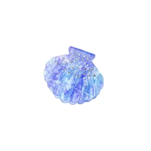 Elegant seashell hair claw with blue marble texture, rhinestones and pearls on white background