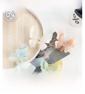Detailed macro of gradient butterfly hair claws in pastel resin on a wooden tray