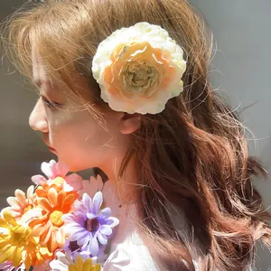 Elegant cream-colored peony flower hair claw clip worn by a model in soft sunlight