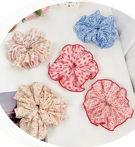 Set of five floral fabric scrunchies with various patterns on a clean white desk surface