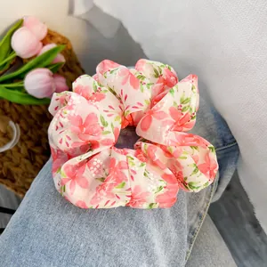 Dettaglio dello scrunchie floreale in chiffon con motivo a fiori rosa su denim