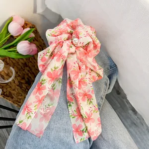Dettaglio dell'elastico per capelli in chiffon floreale con perla decorativa