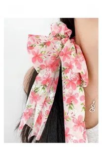 Dettaglio di uno scrunchie in tulle a fiori rosa con lunghi nastri su uno chignon