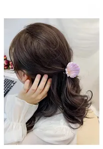 Detail of shell hair claw clip with purple pearlescent finish and pearl on wavy hair