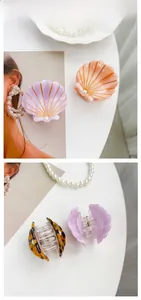 Detailed views of shell-shaped acetate hair claws with pearls in multiple colors