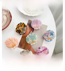 Shell-shaped acetate hair claws in various colors with pearl accents and gold details