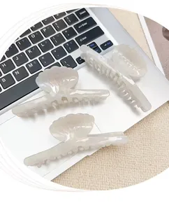 Tre fermagli per capelli a conchiglia bianco iridescente su una tastiera laptop