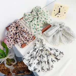 Floral chiffon bow scrunchies in various patterns on a cozy white fabric background
