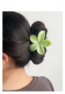 Détail d'une pince à cheveux fleur vert crème portée dans un chignon quotidien