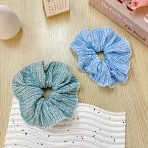 Set di due elastici per capelli floreali increspati in azzurro su tavolo in legno