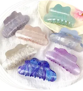 Detail of 7 colorful cloud-shaped acrylic hair claws with marble texture and glitter finish