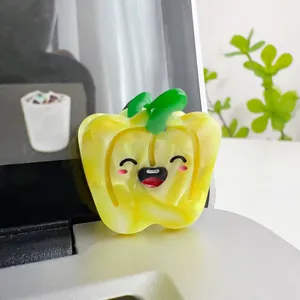 Close-up of yellow bell pepper hair clip with cute cartoon face and marble texture