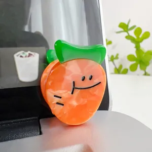 Close-up of a cute orange fruit acetate hair claw clip with smiling face on laptop screen