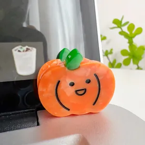 Detail showing high-quality acetate pumpkin hair claw clip with cute smiling face design