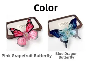 Detailed view of acrylic butterfly hair claws in pink and blue on a wooden tray