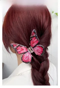 Close-up of pink butterfly acrylic hair claw clip used for styling a braided updo