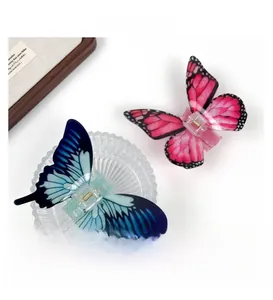 Macro view of blue and pink acrylic butterfly hair claws with detailed wing textures