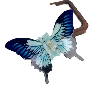 Elegant gradient blue acrylic butterfly hair claw clip with golden metal spring on wood