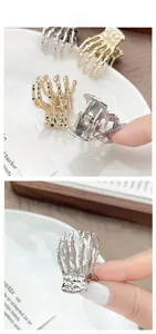 Detailed close-up of golden and silver skull hand claw hair clips with spring mechanism