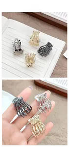 Detailed view of skull hand mini claw clips in silver, gold, and gunmetal finishes