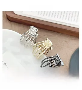 Detailed view of three metallic skeleton hand hair clips in silver gold and gunmetal gray