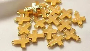 Makroaufnahme von vergoldeten Kreuzanhängern mit zwei Verbindungsringen für DIY-Schmuck