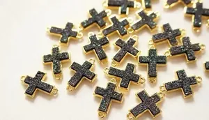 Detail von vergoldeten Kreuzanhängern mit dunkler Kristalleinlage für DIY-Schmuck