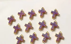 Detailansicht von 13 lila Glitzer-Kreuzanhängern mit Goldbeschichtung für DIY-Schmuck
