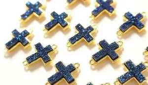 Detailansicht von blauen Druzy-Kreuzanhängern mit Goldbeschichtung und doppelten Ösen