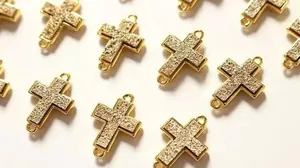Makro-Detail von vergoldeten Kreuzanhängern mit Mikro-Pave-Textur für DIY-Schmuckherstellung