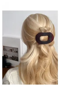 Detail of dark amber matte oval hair clip worn on blonde hair for elegant styling