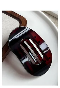 Close-up of oval tortoiseshell hair clip with hollow design on a wooden tray