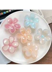 Dettaglio di sei mollette per capelli a forma di fiore di frangipane in resina lucida