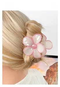 Detail of pink and white frangipani flower hair claw clip on blonde hair updo