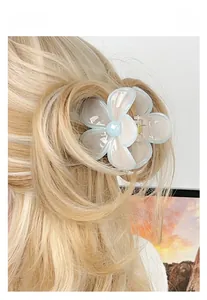Detail of light blue plumeria flower hair claw clip on blonde wavy hair for daily wear