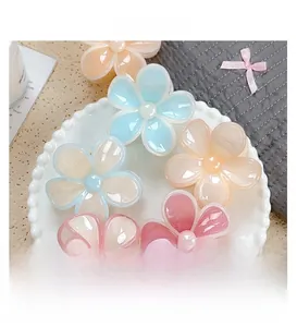 Detailed overhead view of five colorful tropical plumeria flower hair claws in a ceramic dish