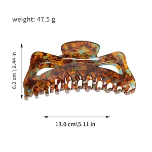 Large tortoiseshell hair claw clip with acetate finish and gold lettering on white background