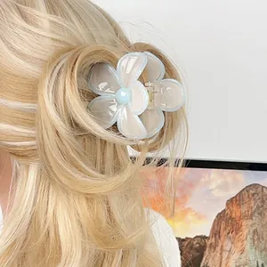 Blue and white plumeria hair claw clip worn on blonde hair for a fresh summer look