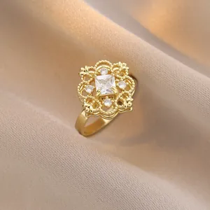 Elegant gold flower ring featuring a square crystal center on satin background