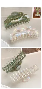 Detail of wave-shaped hair claw clips in pearlescent green and cream white resin